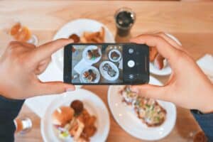 Hands holding a phone in landscape and taking a photo of food in flatlay