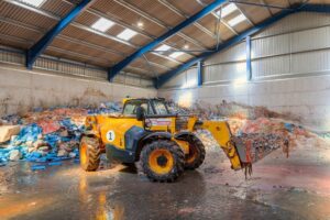 Inside one of BioteCH4 waste plants with a yellow tractor surrounded by food waste for food waste action week